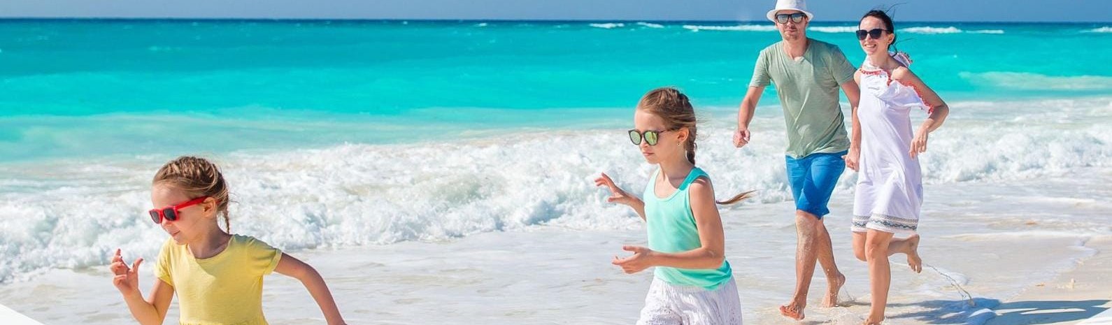 Familia corriendo feliz por la orilla de una playa del Caribe